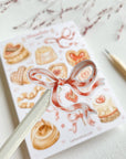 Premium Handmade Sticker Sheet
Chocolate Lover 105mm x 148mm - a piece and a sheet on the table with a dark maroon flower branch, a pencil in the background