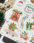Premium Handmade Sticker Sheet Christmas 105mm x 148mm - a sheet on the table with a white flower branch, an opened notebook, a pinecone, a pine branch