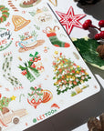 Premium Handmade Sticker Sheet Christmas 105mm x 148mm - a sheet on the table with an opened notebook, 2 pinecones, a red berry branch, a star