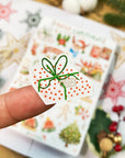 Premium Handmade Sticker Sheet Christmas 105mm x 148mm - a piece and a sheet on the table with an opened notebook, an acorn, a pinecone, 5 stars