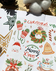 Premium Handmade Sticker Sheet Christmas 105mm x 148mm - a sheet on the table with a white flower branch, an opened notebook, a pinecone, 3 stars