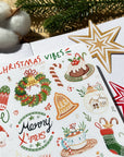 Premium Handmade Sticker Sheet Christmas 105mm x 148mm - a sheet on the table with an opened notebook, a pinecone, 2 stars