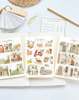 Premium Handmade Sticker Sheet Cozy Doors 105mm x 148mm - 3 sheets on the table with a pencil, an opened notebook, a chapter heading