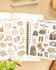 Premium Handmade Sticker Sheet Dark & Light Academia 105mm x 148mm - 2 sheets on the table with a plant branch, an opened notebook, a ruler