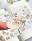 Premium Handmade Sticker Sheet Dark & Light Academia 105mm x 148mm - a piece on the finger and 2 sheets on the table with an opened notebook