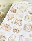 Premium Handmade Sticker Sheet Dark & Light Academia 105mm x 148mm - a sheet on the table with an opened notebook, a white flower branch