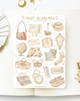 Premium Handmade Sticker Sheet Dark & Light Academia 105mm x 148mm - a sheet on the table with an opened notebook, a white flower branch