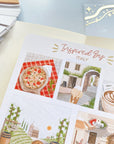 Premium Handmade Sticker Sheet Inspired by Italy 105mm x 148mm - a sheet on the table with an opened notebook