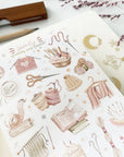 Premium Handmade Sticker Sheet Knitting Crochet 105mm x 148mm - a sheet on the table with a dark maroon flower branch, an opened notebook, a pencil, a ruler