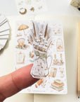 Premium Handmade Sticker Sheet Magical Cozy Fall 105mm x 148mm - a piece and a sheet on the table with a pencil, an opened notebook