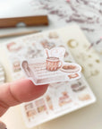 Premium Handmade Sticker Sheet Reading at Home 105mm x 148mm - a piece on the finger and a sheet on the table with a dark maroon flower branch, an opened notebook, a pencil, a ruler