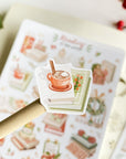 Premium Handmade Sticker Sheet
Reading in the Winter 105mm x 148mm - a piece and a sheet on the table with a branch, a red berry branch