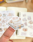 Premium Handmade Sticker Sheet Reading Time 105mm x 148mm - a piece and 2 sheets on the table with an opened notebook in the background