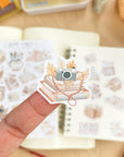Premium Handmade Sticker Sheet Reading Time 105mm x 148mm - a piece and 2 sheets on the table with an opened notebook in the background
