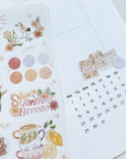 Premium Handmade Sticker Sheet Summer Breeze 105mm x 148mm - a piece above the calendar and a sheet on the table with a pencil, an opened notebook