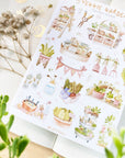 Premium Handmade Sticker Sheet
Veggie Garden 105mm x 148mm - a sheet on the table with a white flower branch, an opened notebook, a plant branch