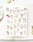 Premium Handmade Sticker Sheet Wild Flower 105mm x 148mm - a sheet on the table with a white flower branch, an opened notebook