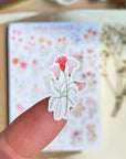 Premium Handmade Sticker Sheet Wild Flower 105mm x 148mm - a piece on the finger and a sheet on the table with a white flower branch, an opened notebook