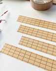 Premium Handmade Washi Tape Brown Grid 15mm x 10m - 4 pieces and a washi tape on the table with a dark maroon flower branch