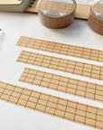 Premium Handmade Washi Tape Brown Grid 15mm x 10m - 4 pieces and 2 washi tapes on the table with a dark maroon flower branch, a notebook