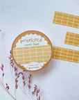 Premium Handmade Washi Tape Butterscotch Grid 15mm x 10m - 3 pieces and a washi tape on the table with a dark maroon flower branch