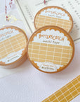 Premium Handmade Washi Tape Butterscotch Grid 15mm x 10m - a piece and 3 washi tapes on the table with a dark maroon flower branch, a sticker sheet, a chapter heading