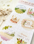 Premium Handmade Sticker Sheet A Day At Home 105mm x 148mm - a sheet on the table with a white flower branch, an opened notebook