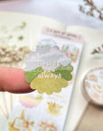 Premium Handmade Sticker Sheet A Day At Home 105mm x 148mm - a piece on the finger and a sheet on the table with a white flower branch, a purple flower branch, a washi tape, an opened notebook