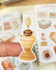 Premium Handmade Sticker Sheet Aesthetic Book 105mm x 148mm - a piece on the finger and 2 sheets on the table with an opened notebook