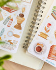 Premium Handmade Sticker Sheet Aesthetic Book 105mm x 148mm - 2 sheets on the table with a plant branch, an opened notebook