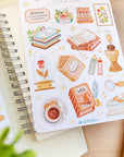 Premium Handmade Sticker Sheet Aesthetic Book 105mm x 148mm - 2 sheets on the table with a plant branch, an opened notebook