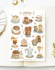 Premium Handmade Sticker Sheet Coffee 105mm x 148mm - a sheet on the table with a white flower branch, an opened notebook