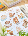 Premium Handmade Sticker Sheet Coffee 105mm x 148mm - = sheet on the table with a plant branch, an opened notebook