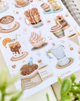 Premium Handmade Sticker Sheet Coffee 105mm x 148mm - a sheet on the table with a plant branch, an opened notebook