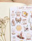 Premium Handmade Sticker Sheet Dark Magic 105mm x 148mm - a sheet on the table with a white flower branch, an opened notebook