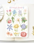 Premium Handmade Sticker Sheet Floral Power 105mm x 148mm - a sheet on the table with a white flower branch, an opened notebook