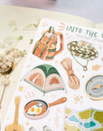 Premium Handmade Sticker Sheet Into The Wild 105mm x 148mm - a sheet on the table with a white flower branch, an opened notebook