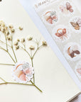 Premium Handmade Sticker Sheet Magic Wings 105mm x 148mm - a piece on the white flower branch and a sheet on the table