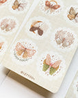 Premium Handmade Sticker Sheet Magic Wings 105mm x 148mm - 3 sheets on the table with an opened notebook