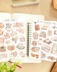 Premium Handmade Sticker Sheet Reading Time 105mm x 148mm - 2 sheets on the table with a plant branch, an opened notebook