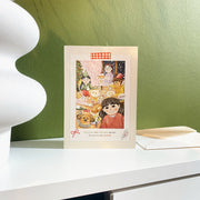 Same Food Same People Christmas card, English front, styled on a shelf with its envelope