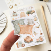Premium Handmade Sticker Sheet 
Aesthetic Cozy 105mm x 148mm - a piece on the finger and a sheet on the table with a pencil, an opened notebook