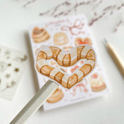 Premium Handmade Sticker Sheet 
Chocolate Lover 105mm x 148mm - a piece and a sheet on the table with a dark maroon flower branch, a pencil in the background