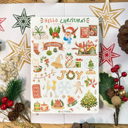 Premium Handmade Sticker Sheet Christmas 105mm x 148mm - a sheet on the table with a white flower branch, an opened notebook, 4 pinecones, a pine branch, 2 red berry branches, 4 stars