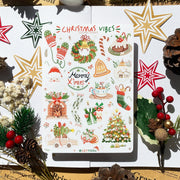 Premium Handmade Sticker Sheet Christmas 105mm x 148mm - a sheet on the table with a white flower branch, an opened notebook, 5 pinecones, 2 pine branches, 2 red berry branches, 5 stars