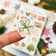Premium Handmade Sticker Sheet Christmas 105mm x 148mm - a piece and a sheet on the table with an opened notebook, an acorn, a pinecone, 5 stars
