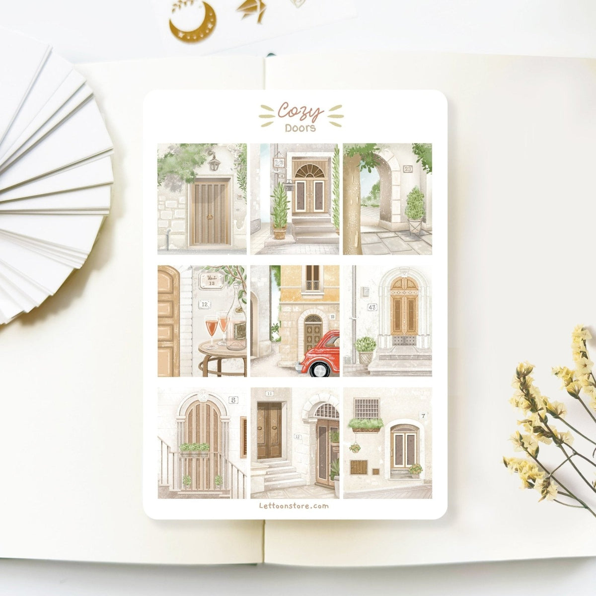 Premium Handmade Sticker Sheet Cozy Doors 105mm x 148mm - a sheet on the table with a white flower branch, an opened notebook