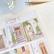 Premium Handmade Sticker Sheet Cozy Doors 105mm x 148mm - a sheet on the table with an opened notebook
