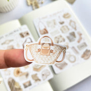 Premium Handmade Sticker Sheet Dark & Light Academia 105mm x 148mm - a piece on the finger and 2 sheets on the table with an opened notebook