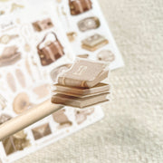 Premium Handmade Sticker Sheet Dark & Light Academia 105mm x 148mm - a piece on the stick and a sheet on the table with an opened notebook